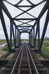 view of the length of railway among old steel bridge with green tree at left and right side of railway,filtered image, light effect added, selective focus