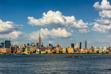 Naklejka premium Wieżowce Manhattan Midtown West i rzeka Hudson z przepływającymi chmurami. Pejzaż w letnie popołudnie w Nowym Jorku z widokiem na Midtown i West Village