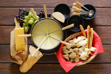 Traditional set of utensils for fondue, with bread, cheese and grapes