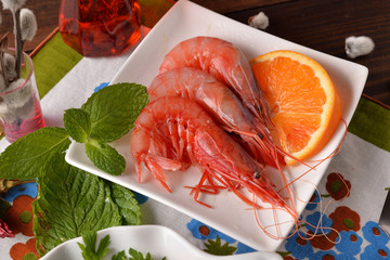 Serving of raw shrimp with orange slice and mint
