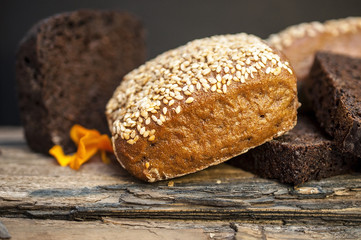 White, gray and black bread with sesame and saffron on the old wooden table at a small village kitchen