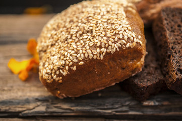 White, gray and black bread with sesame and saffron on the old wooden table at a small village kitchen