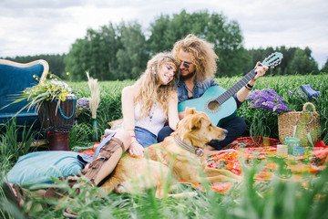 Young pretty hippie couple with guitar and dog outdoor