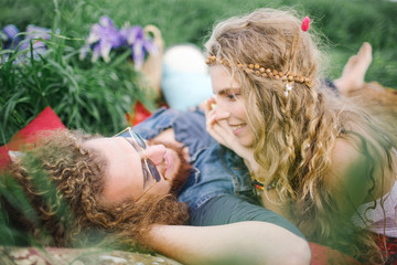 Young beautiful hippie couple lying on grass having fun