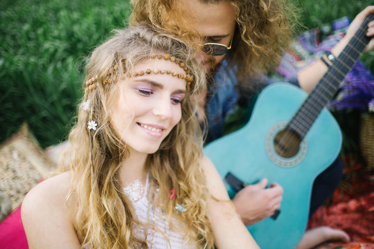 Young pretty curly hippie couple with guitar outdoor