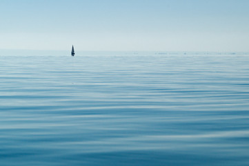 Minimalism: A lone sail away on a clean lake