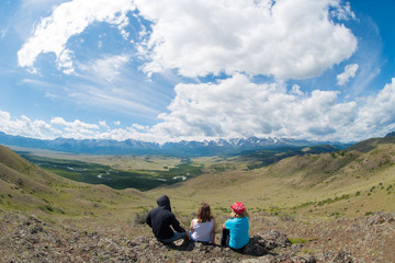 Fototapeta premium man and two girls sitting on mountain slope