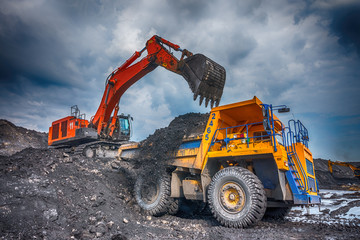 NOVOKUZNETSK, RUSSIA - JULY 26, 2016: Big yellow mining truck and excavator at worksite
