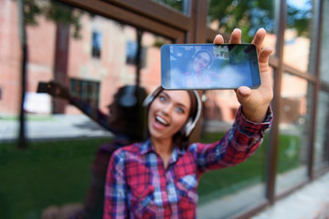 Joyful hipster girl photographing herself