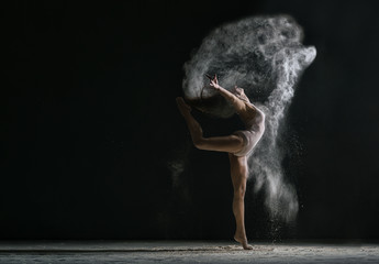 Concept. Flexible girl dancing in cloud of dust - obrazy, fototapety, plakaty