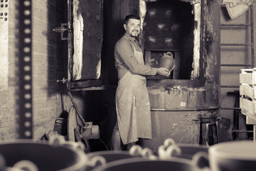 positive male with black-glazed ceramic vase standing close to k