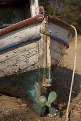 Old fishing boat stern with a blue propeller on dry land