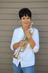 Female jazz trumpet player holding her horn outside.