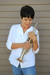 Female jazz trumpet player holding her horn outside.