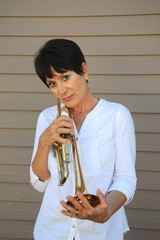 Female jazz trumpet player holding her horn outside.