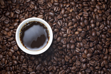 black coffee in a white cup placed on coffee beans.