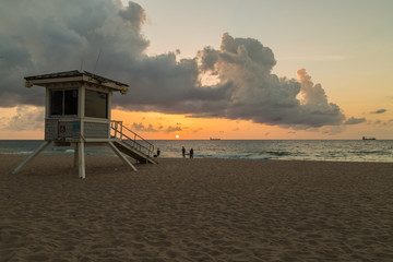 Lifeguard tower/ People on the beach enjoying beautiful sunrise.
