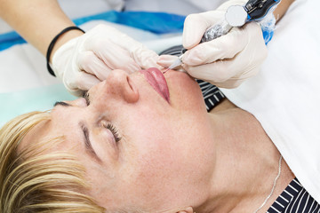 Obraz na płótnie Canvas Lip tattoo woman in a beauty salon process