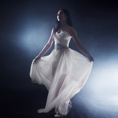 Beautiful sexy young woman. Portrait of girl in long white dress, mystical, mysterious style, dark background