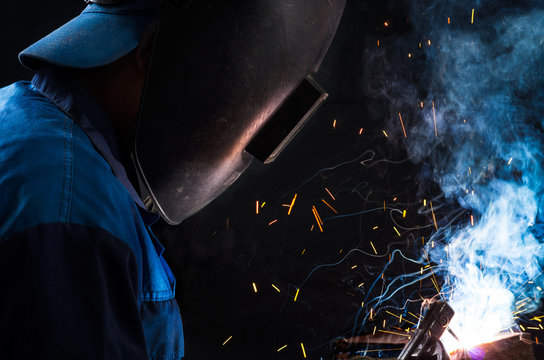 Welder in blue overalls - Powered by Adobe