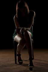 Fototapeta premium nierozpoznawalna kobieta siedząca w ciemności na krześle
