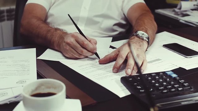 Director at the desk, reviewing business documents, rasspisyvaesya documents.
