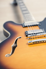 Fototapeta na wymiar Electric jazz guitar close up on an orange sunburst color and chrome electronics