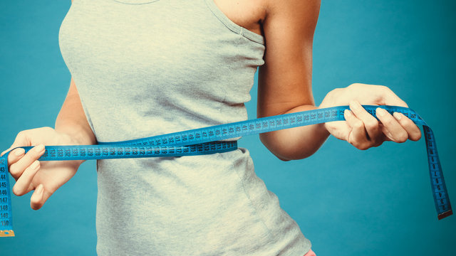 Fitness girl measuring her waistline