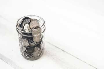 Coins in a jar of glass. Coins on a wooden background.