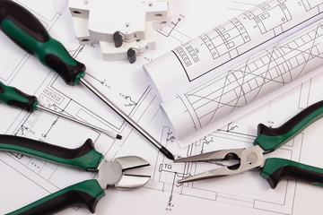 Work tools, electric fuse and rolls of diagrams on construction drawing of house
