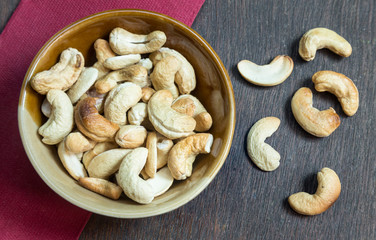 Bowl of cashew nuts from above. On wood background.
