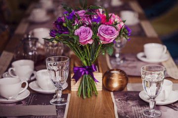 Flowers composition in restaurant, roses and irises, combination shades of purple