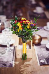 Flowers composition in restaurant, roses and irises, combination shades of purple