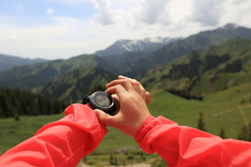 young woman hiker checking the altimeter on sports watch at mountain peak