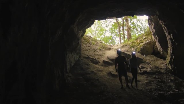 Young couple: Defocused people silhouettes with flashlights in the cave