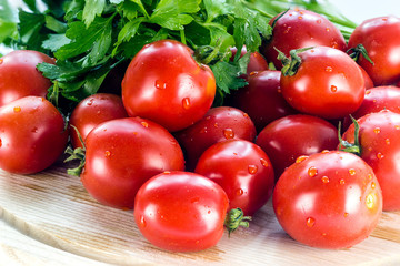 group of red ripe tomatoes and parsley on a wooden board