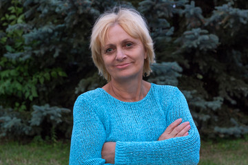 Smiling happy ellderly woman stands with crossed arms