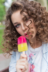 beautiful girl with curly with a naked sexy lips eating color ice cream in a cafe in the park a bright summer day