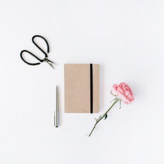 pink rose, scissors, craft diary and pen on white background. flat lay, top view
