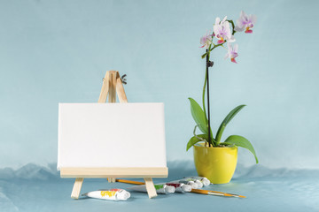 Still life with easel with a blank canvas, watercolor and  orchi