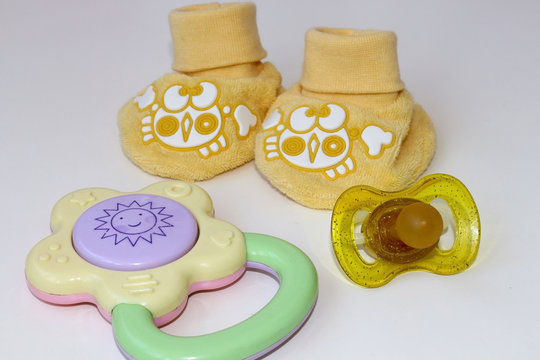 Set for newborn booties shoes pacifier and toy NP light background.