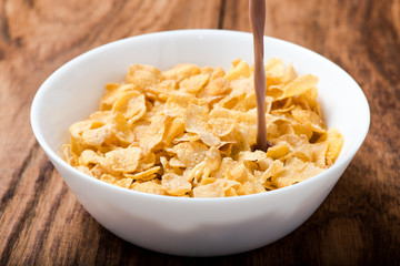 cornflakes cereal pouring chocolate milk on wood table