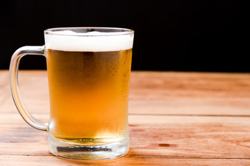 Beer pouring from top in bottle on wood table