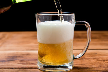 Beer pouring from top in bottle on wood table