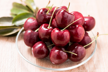 Cherries in plate on wooden table