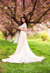 Fototapeta premium beautiful spring walk in the woods among the cherry blossom in Aprila lady in a long dress pastel , creative computer colors, fashionable toning