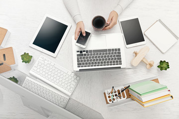 Concept of using electronics. Businesswoman works at office. Computer, laptop, tablet, cup of...