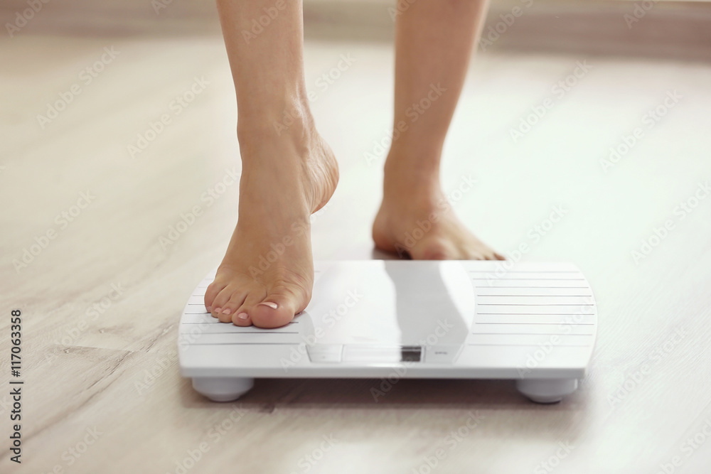 Wall mural Female leg stepping on floor scales