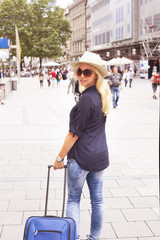 Woman with sun hat and suitcase in the city