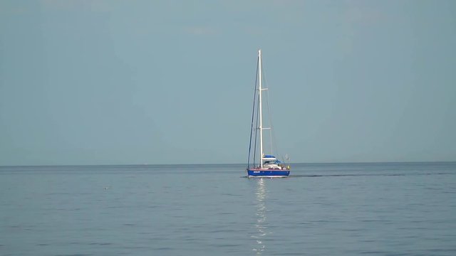 The yacht with the lowered sails floating in the sea. Slow motion,high speed camera